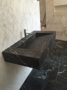 a black marble sink in a bathroom with white tiles on the walls and flooring