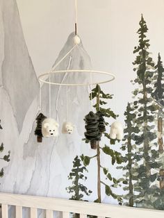 a baby crib with pine cones hanging from it's sides and bears in the trees