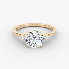 a yellow gold engagement ring with three stones on the side and an oval diamond center