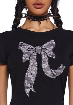 This graphic tee has a stretchy knit construction, short sleeves, and a textured lace bow graphic on the front with stud detailing. Edgy Party T-shirt With Graphic Print, Edgy Graphic Print T-shirt For Party, Black Cotton T-shirt For Party, Black Graphic Tee For Party, Grunge Short Sleeve T-shirt For Night Out, Short Sleeve Cotton T-shirt With Lace Trim, Cotton T-shirt With Lace Trim, Cotton T-shirt With Lace Trim And Short Sleeves, Cotton T-shirt With Lace Trim, Short Sleeve