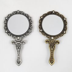 two mirrors sitting next to each other on top of a white wall with an ornate design