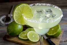 a margarita cocktail garnished with limes on a cutting board