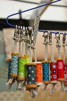 several spools of thread are hanging from a hook on a sewing needle rack