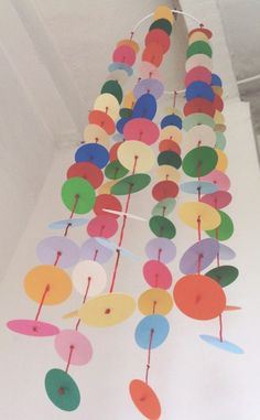 a multicolored wind chime hanging from the ceiling in a room with white walls