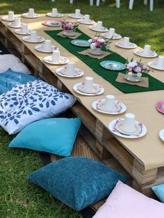 a long table set up with tea cups and saucers on it for a party