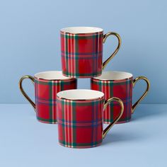 three red and green plaid mugs sitting next to each other on a blue surface