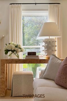 a living room filled with furniture and a lamp on top of a wooden table in front of a window