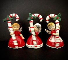 three christmas figurines with candy canes in the shape of angels on black background