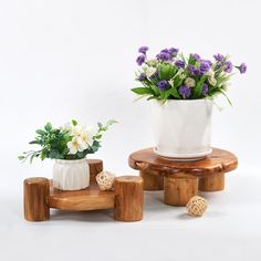 two small wooden stools with flowers in them on a white background, one is holding a potted plant