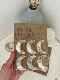 a package of moon magnets sitting on top of a table next to a vase