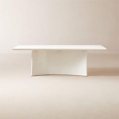 a white table sitting on top of a floor next to a beige wall and chair