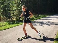 a woman riding skis down a road next to trees