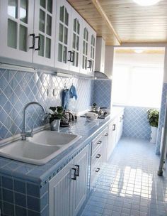 a kitchen with white cabinets and blue tile on the counter tops, along with a sink