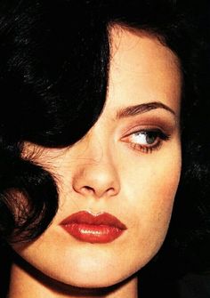 a close up of a woman with dark hair and red lipstick on her face, looking to the side