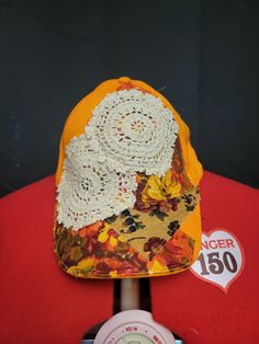 an orange hat with white crochet sits on top of a red tablecloth