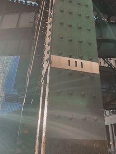 the side of a bridge that is green with metal rivets