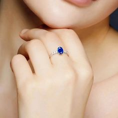 a close up of a woman's hand with a blue ring on her finger