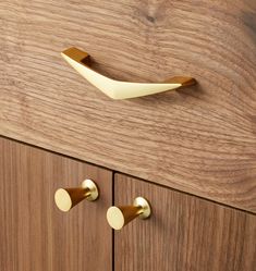 a wooden cabinet with two brass handles and knobs on it's sides, next to a pair of door pulls