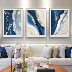 three paintings are hanging on the wall above a coffee table in a modern living room