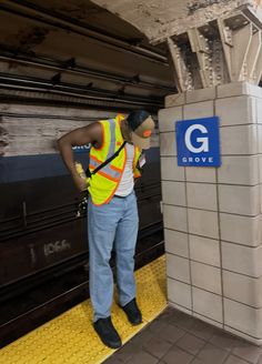 a man in safety vest standing next to a subway station sign with the g logo on it