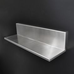 a metal shelf mounted to the side of a wall in a black room with white walls