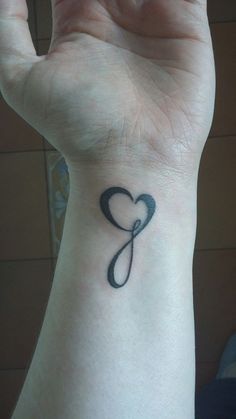 a woman's wrist with a heart tattoo on it