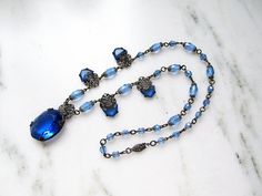 "This is a gorgeous antique Art Nouveau blue glass bead pendant necklace. The metal is sterling silver. There are lovely filigree pieces that hold the glass stones. The large oval pendant measures 1 5/8\" x 3/4\". The necklace is 22\" long. It has a secure sterling silver box clasp. Unsigned. This is an antique, previously owned necklace. Therefore, light wear can be expected. There is no visible damage." Antique Blue Gemstone Necklaces, Victorian Blue Gemstone Necklace, Vintage Blue Oval Pendant Necklace, Vintage Blue Oval Bead Necklace, Vintage Blue Necklace With Oval Beads, Vintage Blue Necklaces With Oval Beads, Ornate Blue Pendant Necklace, Ornate Blue Necklace With Intricate Design, Ornate Blue Oval Jewelry