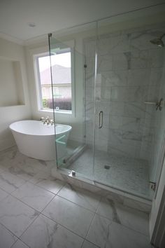 a white bath tub sitting next to a window in a bathroom with marble flooring