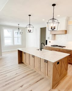 a large kitchen with an island in the middle and two pendant lights hanging from the ceiling