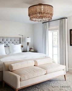 a bedroom with a bed, couch and chandelier