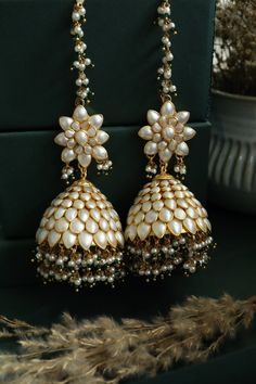 This statement pair features patchi work in a delicate creamish white color and embellished with pearls and green stones. These earrings with their artistic aesthetics are undoubtedly a stunner. Closure - Push Back Style Tip - Wear this with almost anything Indian for a rich and royal look because nothing more regal than patchi work earrings. We love teaming this with classy chiffon sarees or zari silk sarees. Also looks best when worn with your royal whites, off whites and gold. We recommend st Luxury Green Jhumkas As Gift, Luxury Green Jhumkas For Gift, Luxury Traditional Pearl Earrings With Latkans, Luxury Green Hand Set Jhumkas, Luxury Hand-set Green Jhumkas, Luxury Green Chandbali Jhumkas, Luxury Green Jhumkas For Diwali, Luxury Green Bollywood Jhumkas, Luxury Green Elegant Jhumkas