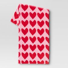 a pink and red towel with hearts printed on the front, folded in two rows