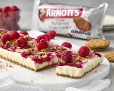 raspberry cheesecake with granola toppings on white plate next to cookies