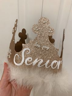 a hand holding up a gold and white crown