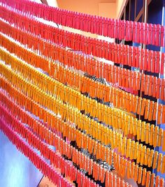 there are many orange and yellow sticks hanging on the wall