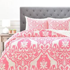 a bed with pink and white comforter in a bedroom next to a night stand