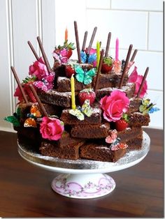 a cake that is sitting on top of a table with candles and flowers in it