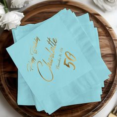 three blue napkins with gold foil on them sitting on top of a wooden plate