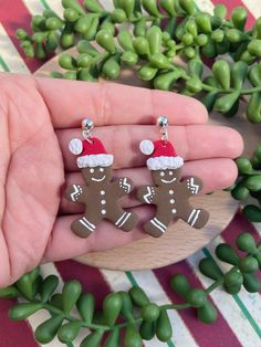 two gingerbreads wearing santa hats and standing next to each other in front of some green plants