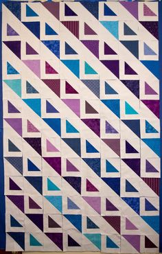 a quilted wall hanging on the side of a blue and purple building with triangles