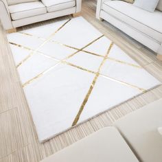 a living room with white couches and gold lines on the rug in front of them