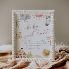 a baby shower sign sitting on top of a bed next to a pile of blankets