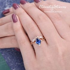 a woman's hand holding a ring with an oval shaped blue sapphire and white diamonds