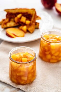 two jars filled with fruit sitting on top of a table next to plates of food