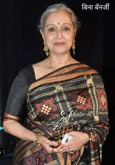 an old woman wearing a sari and posing for the camera with her hands in her pockets