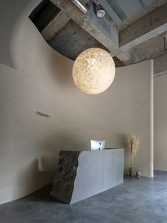 a large white ball hanging from the ceiling above a counter in a room with concrete floors