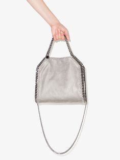 mini Falabella tote from STELLA MCCARTNEY featuring light grey, whipstitch detailing, silver-tone hardware, logo tag, chain-link shoulder strap, two top handles and internal zip-fastening pocket. POSITIVELY CONSCIOUS: We've partnered with Good On You — an ethical agency that rates how sustainably brands perform across various people, planet and animal welfare criteria. This product comes from a Conscious brand that performs well in relation to their impact on animals.. Silver Top Handle Shoulder Bag With Gunmetal Hardware, Silver Shoulder Bag With Top Handle And Chain Strap, Luxury Gray Shoulder Bag With Double Handle, Luxury Gray Shoulder Bag With Dust Bag, Silver Top Handle Bags With Gunmetal Hardware, Gray Top Handle Bag With Handle Drop, Trendy Silver Shoulder Bag With Dust Bag, Chic Silver Shoulder Bag With Double Handle, Silver Shoulder Bag For On-the-go