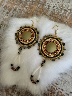 a pair of earrings sitting on top of a white fur covered floor next to a wooden table