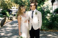 a man and woman dressed in formal wear standing next to each other on a sidewalk