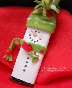 a snowman made out of paper on top of a red blanket with a green hat and scarf